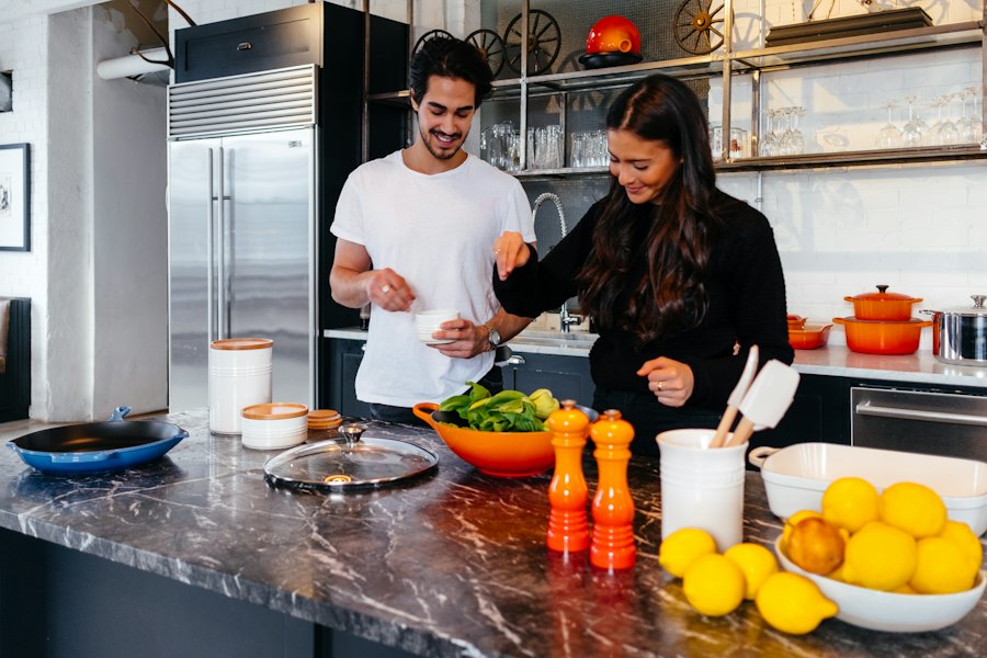 A couple smiling while cooking together in a bright kitchen